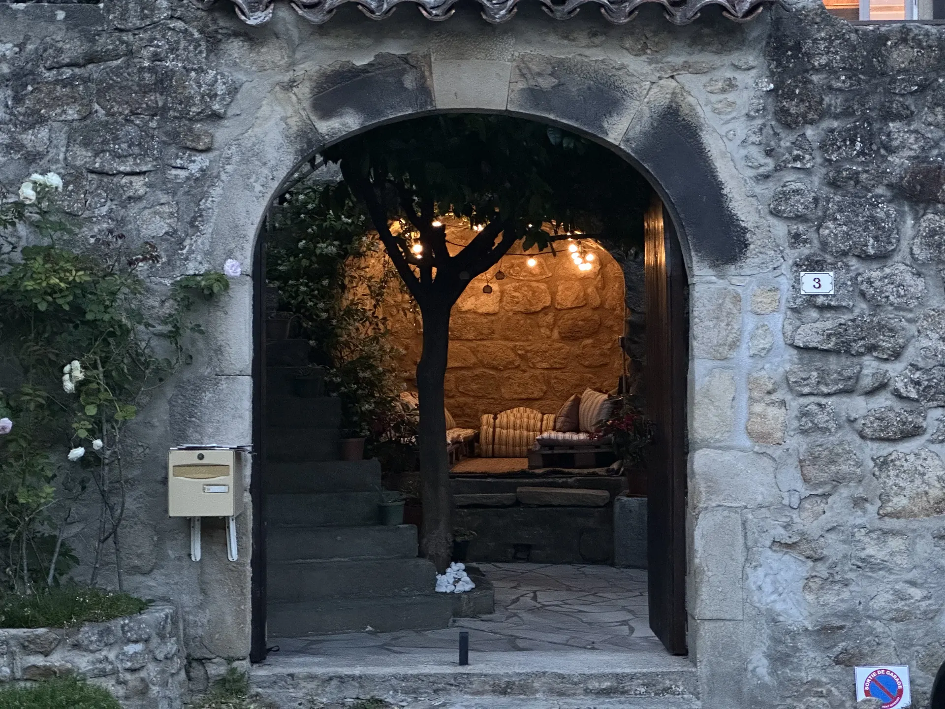 Porche en pierre ouvert sur la cour illuminée